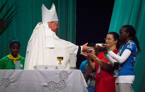 New York Cardinal Timothy M. Dolan receives the gifts from two young women during a Mass at the Rio Vivo Welcome Center in Rio de Janeiro. (CNS photo/Tyler Orsburn)