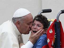 Pope Francis kisses a disabled child. CNS Photo/Paul Haring.