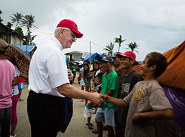 Archbishop Joseph E. Kurtz, president of the U.S. Conference of Catholic Bishops, greets a line of Filipinos in Anibong, a community in Tacloban, Philippines in February 2014. CNS photo/Tyler Orsburn