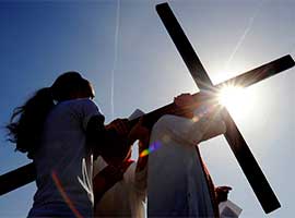 a large cross is transferred from one person to another during the Stations of the Cross in Reparation for Abortion on Good Friday 201  in Rochester, N.Y. CNS photo/Mike rupi, Catholic Courier