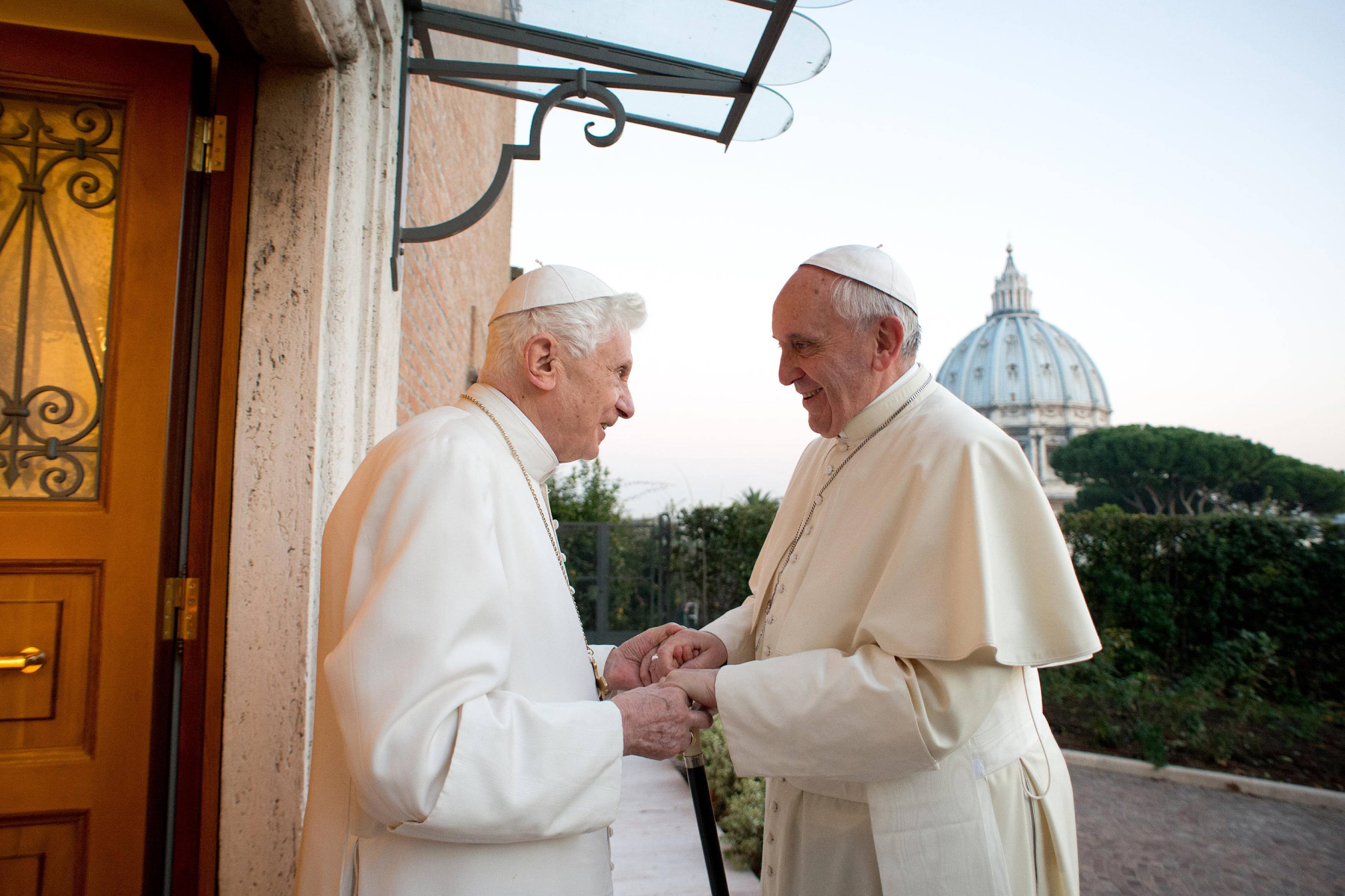 Pope Francis greets retired Pope Benedict XVI.