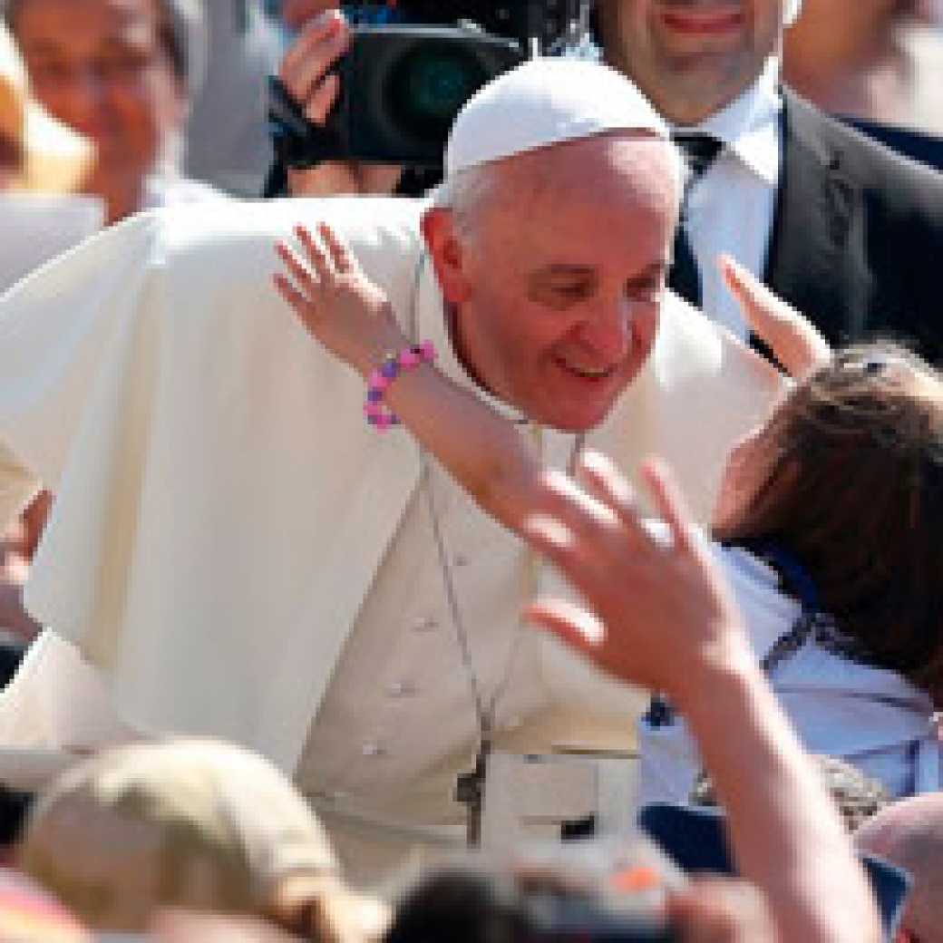 Pope Francis accepts a hug from a girl as he arrives to celebrate Mass in St. Peter's Square at the Vatican. (CNS photo/Paul Haring)